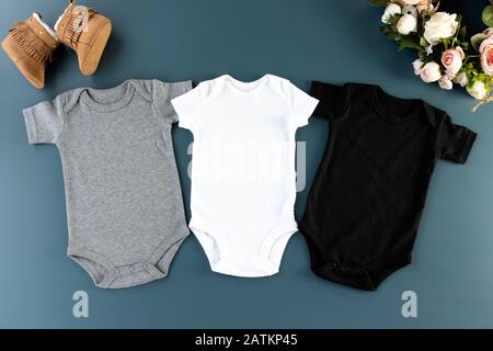 Tre bodysuit su sfondo blu mockup - 3 baby cresce piatto (bianco, grigio e nero) Foto Stock