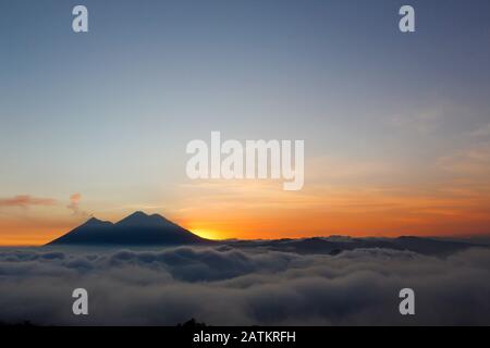 Tramonto sul vulcano di fuoco e vulcano Acatenango - vulcani circondati da nuvole Foto Stock