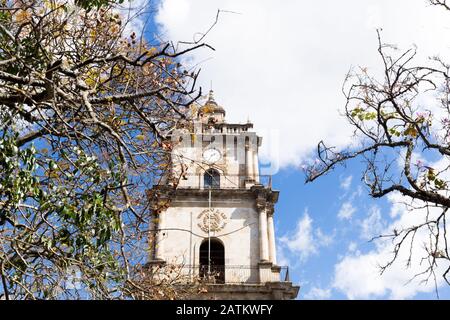 Vecchia torre di pietra con orologio circondato da alberi in autunno in Guatemala Foto Stock