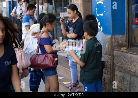 I bambini che vendono le maschere facciali protettive su una strada laterale in Cebu City,Philippines.With la prima morte di Coronavirus registrata recentemente nel paese più gente stanno prendendo le precauzioni per impedire l'infezione. Foto Stock