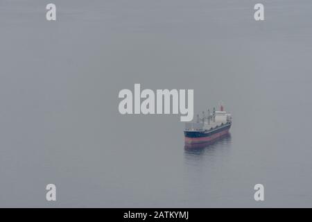 Enorme nave da carico in barca a vela nel mezzo dell'oceano. È molto misty. Vista aerea su una nave con container. Foto Stock