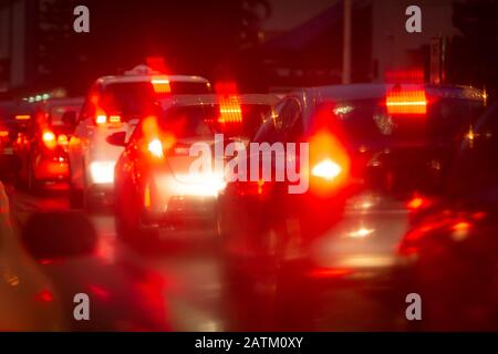 Automobili nella notte ingorgo di traffico con bokeh astratto causato da gocce di pioggia che riflettono Foto Stock