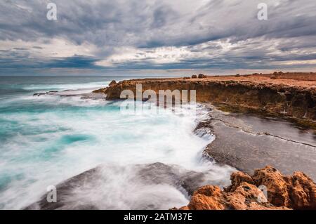 Il tempo selvaggio libra le scogliere e la piattaforma rocciosa della costa frastagliata della stazione di Woroorra nella costa nord occidentale dell'Australia occidentale. Foto Stock