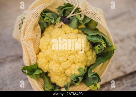 Cavolfiore in un sacchetto riutilizzabile su un'elegante superficie della cucina in legno. Concetto di zero sprechi Foto Stock