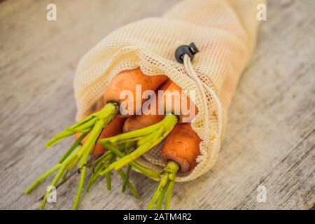 Carota in una borsa riutilizzabile su un'elegante superficie in legno della cucina. Concetto di zero sprechi Foto Stock