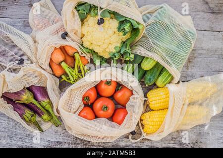 Verdure diverse in sacchetti riutilizzabili su sfondo di legno. Concetto di zero sprechi Foto Stock