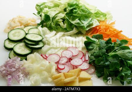 Primo piano di verdure affettate sul tagliere bianco per insalata. Foto Stock