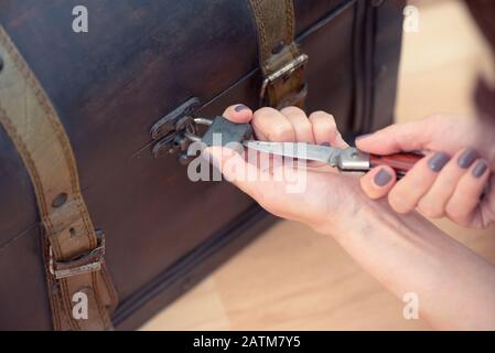 Primo piano delle mani della donna che apre un vecchio petto con un coltello Foto Stock