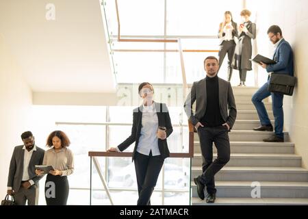 Giovani imprese ambiziose che si alzano in piedi su scale e lavorano come team, concetto di personale aziendale Foto Stock