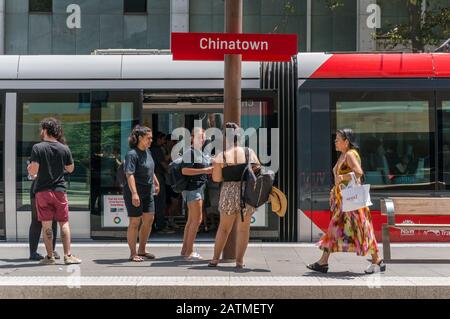 Sydney, Australia - 26 gennaio 2020: Persone che utilizzano la macchina di automazione dei biglietti tap-on-tap presso la stazione della metropolitana leggera di Chinatown con tram rosso su Th Foto Stock