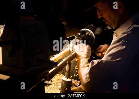 Un artigiano di posate di legno al lavoro nella sua bottega del mercato medina a Marrakech, Marocco Foto Stock