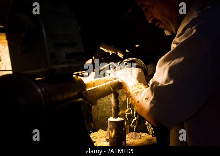 Un artigiano di posate di legno al lavoro nella sua bottega del mercato medina a Marrakech, Marocco Foto Stock