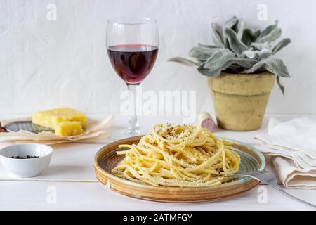 Spaghetti di pasta romana con pepe nero e formaggio. Cacio e pepe. Vino. Ricette. Cibo vegetariano. Cucina nazionale. Sfondo bianco. Foto Stock