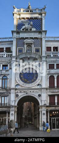 Un panorama verticale della torre dell'orologio di San Marco, dell'orologio zodiaco, del campanile e dell'arco monumentale nella via principale della città, la Merceria. Foto Stock