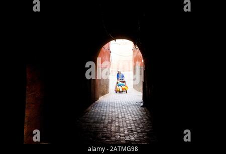 Un uomo spinge un barrow attraverso la medina di Marrakech, Marocco Foto Stock