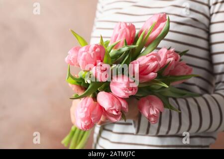 Donna che tiene bouquet di tulipani su sfondo marrone, primo piano Foto Stock