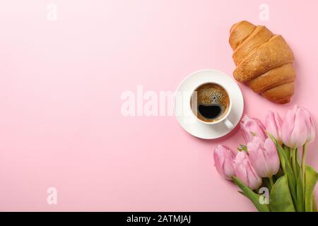 Tulipani, croissant e una tazza di caffè su sfondo rosa, vista dall'alto Foto Stock