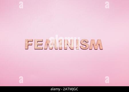 La parola femminismo in lettere di legno su sfondo rosa Foto Stock