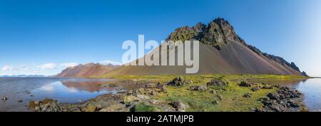 Panorama epico della spiaggia di sabbia nera a Stokksnes in una giornata di sole. Il monte Vestrahorn sullo sfondo. Natura ed ecologia di concetto di fondo. Foto Stock