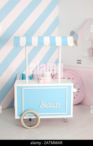 Carrello Con Candy Bar. Camera decorata per un compleanno. Arredamento per le vacanze. Zona per bambini con dolci: Lecca-lecca, gelato e caramella bar. Foto Stock