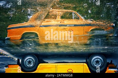 Un taxi giallo Ambassador si riflette sull'acqua di strada a Kolkata, in India. Foto Stock