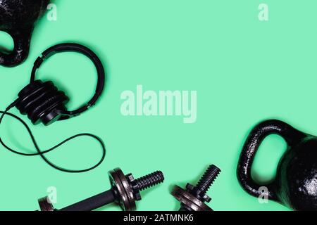 Foto sportive. Kettlebells e manubri di menta su sfondo verde. Appartamento laico, vista dall'alto, copia dello spazio. Foto Stock