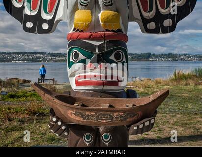 Figura di Wise Man tenere una canoa, totem pole al riparo in Nuyumbalees Native Garden a Cape Mudge villaggio, Quadra Island, British Columbia, Canada Foto Stock