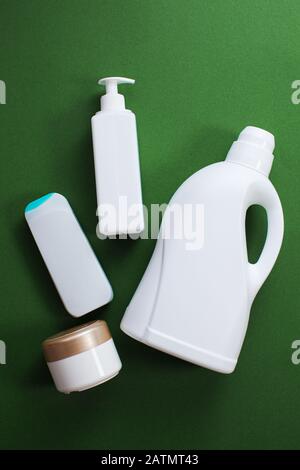 Prodotti chimici domestici o detersivo liquido per bucato e altro detergente su sfondo verde, vista dall'alto, piatto. Foto Stock