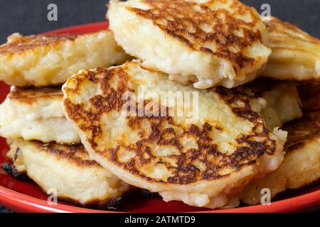 Il formaggio frittelle di formaggio piatto si trova in rosso piatto.Fotografia su sfondo scuro primo piano Foto Stock