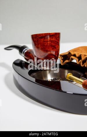 tubo marmorizzato rosso sul posacenere con tappo per tubo, tabal e sacchetto di tabacco Foto Stock