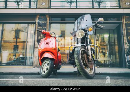 Vienna - Gennaio 12th, 2020: Scooter Vespa rosso vintage e ciclo nero parcheggiati su una strada vuota della città italiana. Simbolo di coppia, amore, relazioni uomo e. Foto Stock