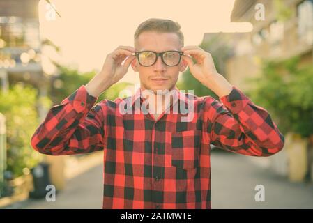 Giovane uomo che indossa rosso a scacchi shirt nelle strade all'aperto Foto Stock