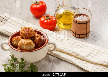 Fritte costolette di carne in ceramica Soup Bowl, pomodori rossi, bottiglia di vetro con olio di semi di girasole, sale in legno canna cantina, asciugatutto e del ramo freschi Foto Stock