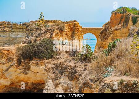 Spiaggia studentesca (Praia dos Estudiantes) in Algarve, Portogallo. Mare e scogliere sullo sfondo. Ponte romano che collega le scogliere sulla spiaggia. Paesaggio a Foto Stock