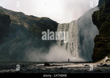 Donna stangg bevore la maestosa cascata skogafoss in Islanda inverno Foto Stock