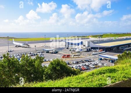 Ponta Delgada, Azzorre, Portogallo - 14 Gennaio 2020: Vista Dell'Aeroporto Di Joao Paulo Ii Nell'Isola Di Sao Miguel. Pista con un aereo, costruzione del terminal e parcheggio per auto a noleggio. Oceano sullo sfondo. Foto Stock