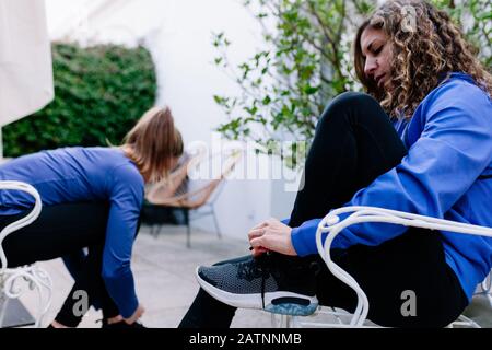 Due giovani sportivi la sua legatura lacci delle scarpe prima del training su una terrazza che indossa felpa. Foto Stock