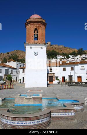 Campanile e fontana nella piazza del paese con il castello sul retro, Jimena de la Frontera, Andalusia, Spagna. Foto Stock