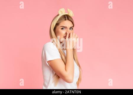 Scioccata ragazza teen che smelling qualcosa di puzzolente allo studio Foto Stock