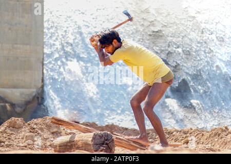 Halon Dam India Feb 02. 2020 : giovani rurali che tagliano il legno di fronte ad una cascata nella diga di Halon. Foto Stock