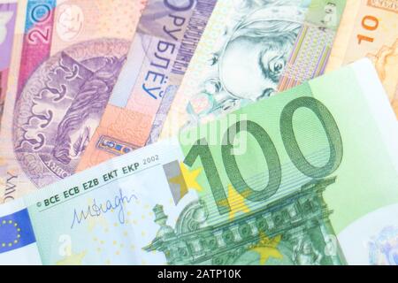 Una banconota da 100 Euro disposta su una pila di banconote iridate di diverse valute mondiali, tra cui euro, Sicli, Rand e Złoty polacche. Foto Stock