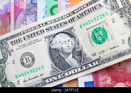 Banconote US Dollar disposte diagonalmente su una pila di banconote iridate di diverse valute mondiali, tra cui euro, Sicli, Rand e Złoty polacche. Foto Stock