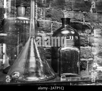 Gli articoli chimici vintage sono sulla mensola su fondo della parete del mattone. Foto in bianco e nero Foto Stock