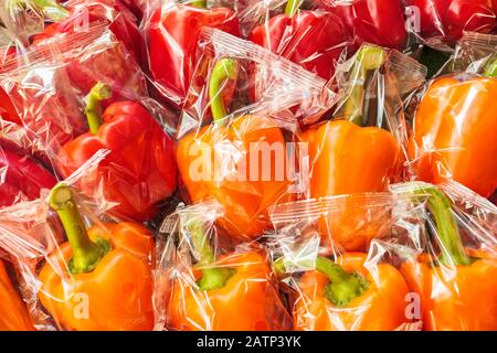 Mazzo di peperoni rossi e arancioni avvolti in plastica Foto Stock