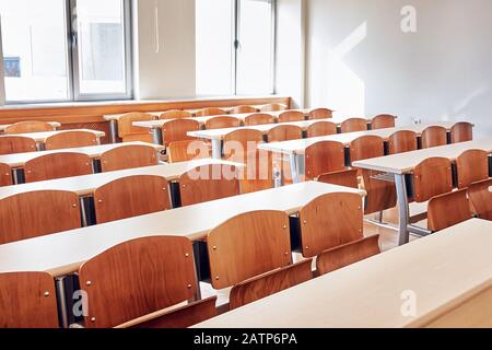 Piccola aula di una sala conferenze universitaria con scrivanie in legno e posti a sedere Foto Stock