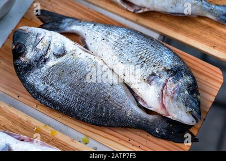 Pesce dorado fresco su piastra di legno pronto per la cottura. Vista dall'alto. Foto Stock