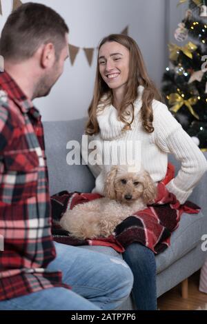 Coppia felice con simpatico e soffice cane che ride sul divano. Foto Stock