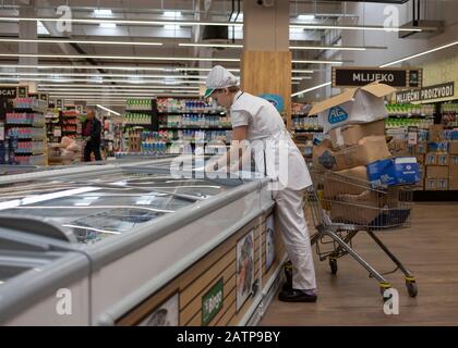 Šamac, Bosnia-Erzegovina, 3 ottobre 2019: Donna dipendente carico supermercato frigorifero Foto Stock