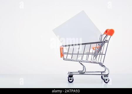 Carrello con una nota bianca su sfondo bianco con spazio di copia. Foto Stock