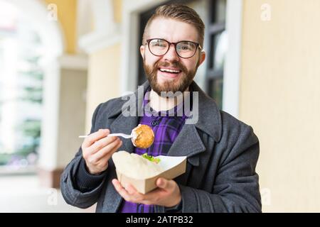 Uomo che tiene un piatto con tradizionale cibo ebreo delizioso falafel fatto di ceci al festival di cibo di strada. Foto Stock